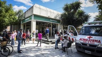 ITUZAINGO, ARGENTINA - APRIL 03: People wait outside Banco Provincia as paramedics on an ambulance give flu shots on April 3, 2020 in Ituzaingo, Argentina. After two weeks of being closed, banks reopen today during quarantine exclusively to pay welfare recipients and retirees who cannot use ATM's. As an extraordinary emergency measure, banks will be open during the weekend. (Photo by Marcelo Endelli/Getty Images)