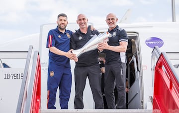 El capitán Jordi Alba, Luis Rubiales y Luis de la Fuente sostienen el trofero de la Nations League al salir del avión