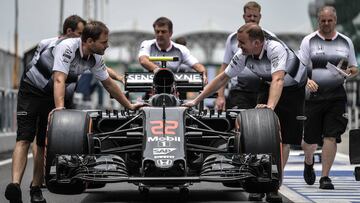 Miembros del equipo McLaren Honda llevando el coche de Jenson Button.