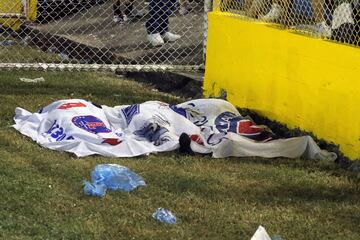 Los cuerpos de las víctimas mortales tras la estampida fueron cubiertos por banderas del club local en el estadio Cuscatlán, el Alianza FC.