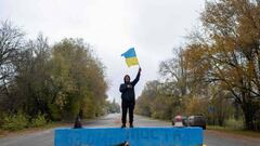 A local resident waves a Ukrainian flag at a former Russian checkpoint at the entrance of Kherson as local residents celebrate the liberation of the city, on November 13, 2022, amid Russia's invasion of Ukraine. - Ukrainians in the liberated southern city of Kherson expressed a sense of relief on November 11, 2022, after months of Russian occupation. There were no scenes of jubilation on November 13, 2022, an AFP correspondent said, but many locals said they felt a great sense of relief after Kyiv had wrested back control of the city. (Photo by AFP) (Photo by -/AFP via Getty Images)