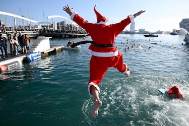 Participants in Santa costumes jump into the water during the 115th edition of the Copa Nadal (Christmas Cup) swimming race in Barcelona's Port Vell on December 25, 2024. The traditional 200-meter Christmas swimming race gathered more than 450 participants on Barcelona's Port Vell. (Photo by Josep LAGO / AFP)