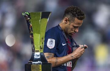 Neymar observando su medalla de primer lugar mientras pasa a un costado del trofeo que más tarde se llevarían a casa