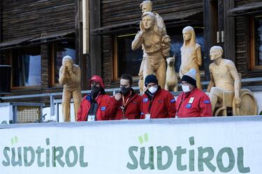 Un grupo de trabajadores de la estación de esquí de Val Gardena, en los Dolomitas, observa la llegada de esquiadores bajo unas estatuas de madera que representan a los aficionados. La estación italiana acoge los días 18 y 19 de diciembre las pruebas de súper gigante y descenso masculinos de la Copa del Mundo de esquí alpino.