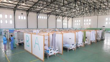 Tunisian doctors are stand next to rows of patients at a gym that was converted to deal with a surge in new COVID-19 infections in the east-central city of Kairouan on July 4, 2021. - Tunisia placed the capital Tunis and the northern town of Bizerte under a partial lockdown from until July 14 in a bid to rein in record daily coronavirus cases and deaths. (Photo by FETHI BELAID / AFP)