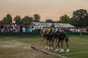 Miembros del staff limpian las líneas de suciedad en una de las pista de Wimbledon