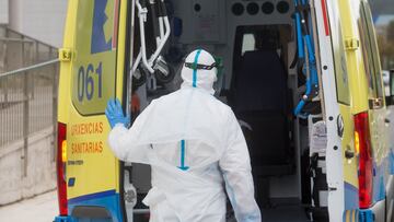 Un trabajador sanitario totalmente protegido cierra la puerta de una ambulancia