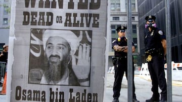 New York police stand near a wanted poster printed on a full page of a New York newspaper for Saudi-born militant Osama bin Laden, in the financial district of New York, U.S., September 18, 2001.