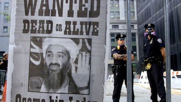 New York police stand near a wanted poster printed on a full page of a New York newspaper for Saudi-born militant Osama bin Laden, in the financial district of New York, U.S., September 18, 2001.