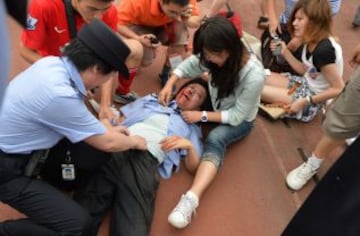 Un policía se trata de lesiones después de ser aplastado en una estampida para poder ver a David Beckham en la Universidad Tonji en Shanghai el 20 de junio de 2013. Cinco personas resultaron heridas cientos de estudiantes entraron por una puerta para ver el ex capitán de Inglaterra, recientemente retirado, que está aquí en una visita de siete días a China.