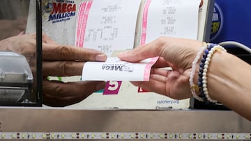 A woman buys a ticket for the Mega Millions lottery drawing at a news stand in New York