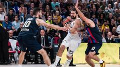 Sergio Lull of Real Madrid  in action against Nico Laprovittola and Nicola Kalinic of FC Barcelona during the Turkish Airlines EuroLeague match between FC Barcelona and Real Madrid at Palau Blaugrana on October 13, 2022 in Barcelona, Spain.