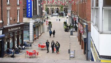 Pedestrians wearing face coverings due to Covid-19 walk along an almost empty shopping street in Blackburn, north west England on June 16, 2021. - The UK government on Monday announced a four-week delay to the full lifting of coronavirus restrictions in England due to a surge in infections caused by Delta, which first appeared in India. (Photo by Oli SCARFF / AFP)