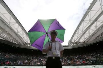 Un guardia de seguridad con paraguas para protegerse de la lluvia en la pista central de Wimbledon