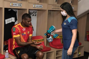 Una empleada desinfecta las manos de Keyner Brown, jugador del Sport Herediano, en el vestuario del equipo. Los clubes profesionales de fútbol de Costa Rica volvieron a los entrenamientos tras más de un mes de confinamiento por el coronavirus.