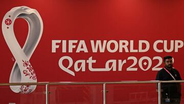 An employee stands in front of the logo of Qatar 2022 FIFA World Cup football tournament at the Host Country Media Centre in Doha on November 3, 2022. (Photo by KARIM JAAFAR / AFP)