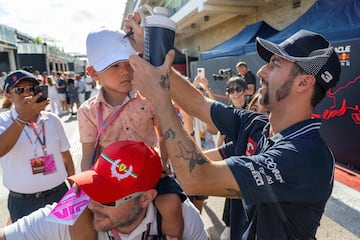 El piloto australiano de Alpha Tauri, Daniel Ricciardo, firma la gorra de un niño en el paddock antes del Gran Premio de Fórmula Uno.