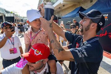 El piloto australiano de Alpha Tauri, Daniel Ricciardo, firma la gorra de un niño en el paddock antes del Gran Premio de Fórmula Uno.