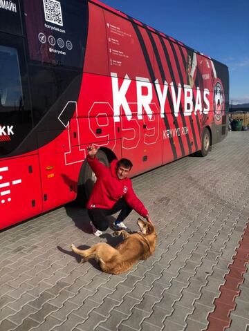 Maksym Tereshchenko juega con un perro frente al autobús de su equipo.