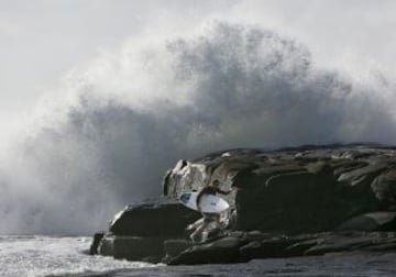 Un surfista se protege detrás de una roca de una ola que se estrella en Angourie Point en la costa norte de Nueva Gales