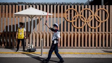 Un policia japon&eacute;s camina en frente de los anillos ol&iacute;mpicos