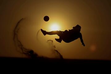 Durante el Mundial de fútbol pudimos sacar la conclusión de que la afición por el balompié se ha multiplicado exponencialmente en Qatar. Como muestra, esta preciosa fotografía, en la que un aficionado golpea un balón con el sol del atardecer y el desierto como testigos. Una auténtica postal.