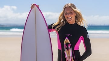 Stephanie Gilmore y su Barbie surfista en la playa, con olas de fondo y una tabla de surf