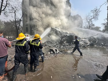 Los miembros del equipo de rescate trabajan mientras el humo se eleva en el lugar donde se estrelló un avión de Air India en Ahmedabad, India.
