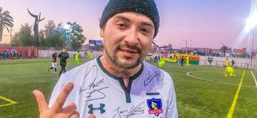 Cristofebril luce una camiseta de Colo Colo que fue autografiada por varios jugadores del club. Sobre la marca, se aprecia la firma de Esteban Paredes.