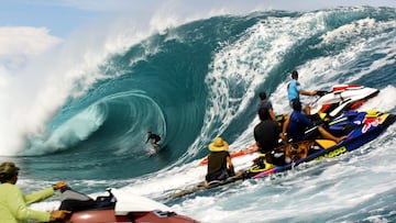 Un surfista surfeando una ola gigante en Teahupo'o, Tahití, Polinesia Francesa, ante la atenta mirada de varias motos de agua.