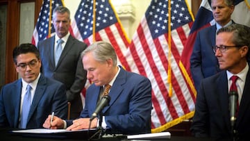 El Representante Estatal Chris Paddie (L) y el Senador Estatal Kelly Hancock (R) observan c&oacute;mo el Gobernador de Texas Greg Abbott firma los Proyectos de Ley del Senado 2 y 3 durante una conferencia de prensa en el Capitolio el 8 de junio de 2021 en Austin. Texas. 
 