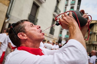 Un asistente bebe vino mientras participa en el inicio oficial de nueve días de fiesta ininterrumpida en el famoso encierro de toros de Pamplona.
