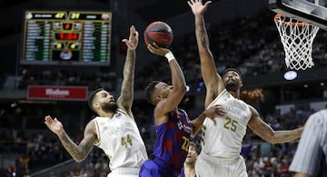 El jugador del Barcelona, Higgins, trata de encestar ante los jugadores del Real Madrid, Taylor y Mickey. 
