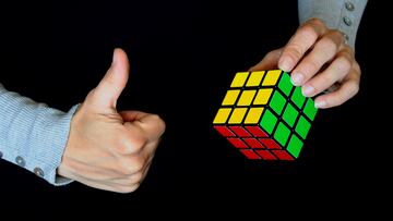Rome, Italy -May 21, 2014: Hands hanging a solved Rubik's Cube on black background. Shot in a studio setting. Rubik's Cube. 3-D mechanical puzzle, invented by Hungarian sculptor and professor Ern? Rubik in 1974. Game solved.