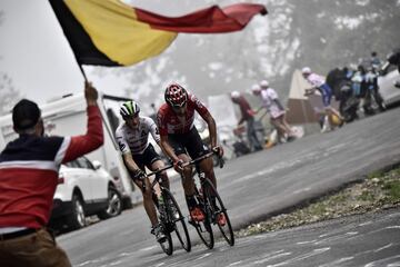 El belga Thomas De Gendt y el británico Stephen Cummings pasando bajo una bandera de Bélgica sostenida por un aficionado presente en la 12ª etapa del Tour de Francia 2017. 