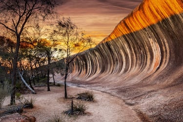 Wave Rock, ubicada cerca de la ciudad de Hyden en el oeste de Australia, es una impresionante formación de granito que imita a la perfección una ola gigante a punto de romper, con unos 15 metros de altura y 110 metros de largo. Geológicamente, es lo que se conoce como una ladera acampanada (flared slope), esculpida durante más de 2,700 millones de años (mucho antes de los dinosaurios) por un proceso de erosión química bajo la superficie del suelo. 