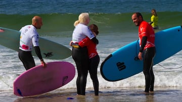 Dos competidoras se abrazan, con las licras de competición y una ola al fondo en la playa de Patos (Nigrán, Galicia), durante el Campeonato de España de surf adaptado 2021, celebrado el 26 de septiembre del 2021.