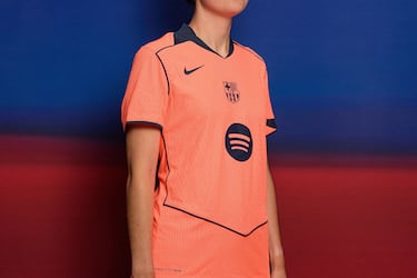 Un llamativo color mango brillante domina en la camiseta –también en los pantalones y las medias– acompañado de varios detalles en azul marino en forma de franjas en el cuello y en la espalda y de filetes que dibujan una forma geométrica en la parte frontal, con el logotipo de Spotify en el centro.