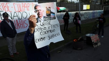 A man holds a placard that reads "Uribe must go to prison. Colombia demands justice" following former Colombia's President Alvaro Uribe's criminal conviction and sentence of 12 years of house arrest, outside the Paloquemao judicial complex, in Bogota, Colombia, August 1, 2025. REUTERS/Luisa Gonzalez