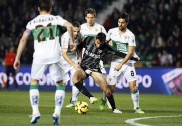 El delantero portugués del Málaga Ricardo Horta (c) lucha un balón con el centrocampista del Elche Adrián González, durante el partido de la decimosexta jornada de Liga de Primera División