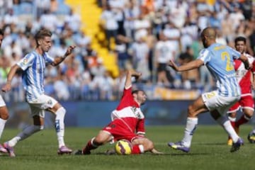 El centrocampista y capitán del Rayo Vallecano Roberto Trashorras (c), cae ante los delanteros del Málaga, Samuel Castillejo (i) y el neerlandés-marroquí Nordin Amrabat, durante el encuentro de la novena jornada de Liga de Primera División que los dos equipos disputan en el estadio de La Rosaleda, en Málaga. 