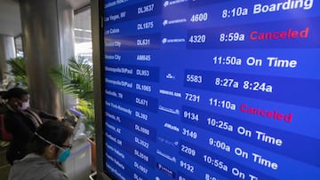 Travelers check for flight information at Los Angeles International Airport in Los Angeles, California, on December 23, 2021. - Over 2,000 flights have been cancelled and thousands delayed around the world as the highly infectious Omicron variant disrupts