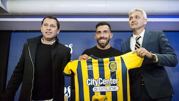 Argentine footballer and new coach of Argentina's Rosario Central football team Carlos Tevez (C) holds his new jersey flanked by the team's manager Raul Gordillo (L) and the team's club vice-president Ricardo Carloni during his presentation, at the Gigante de Arroyito stadium, in Rosario, Santa Fe province, Argentina, on June 21, 2022. (Photo by STRINGER / AFP)