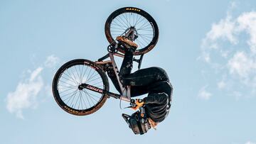 Caroline Buchanan realizando un Flip con su bici de MTB y un cielo despejado con alguna nube de fondo.