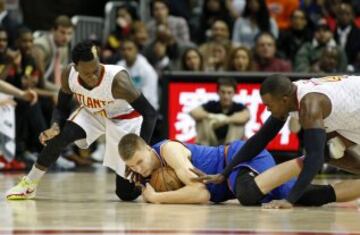 Kristaps Porzingis esconde la pelota ante Dennis Schroder y Paul Millsap.