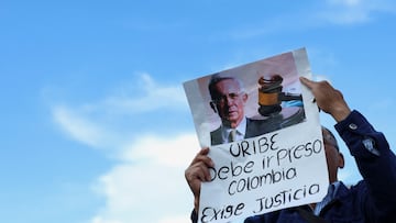 A man holds a placard that reads "Uribe must go to prison. Colombia demands justice" following former Colombia's President Alvaro Uribe's criminal conviction and sentence of 12 years of house arrest, outside the Paloquemao judicial complex, in Bogota, Colombia, August 1, 2025. REUTERS/Luisa Gonzalez