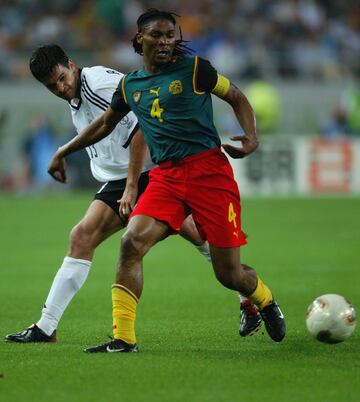 El actual entrenador camerunés jugaba de defensa  y lo hizo en cuatro Mundiales: Estados Unidos 1994, Francia 1998, Corea/Japón 2002 y Sudáfrica 2010.