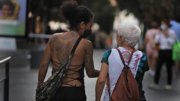 Imagen de dos mujeres caminando juntas por las calles de Barcelona y portando mascarillas.