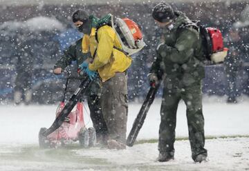 Operarios del club italiano retiran la nieve de las lineas del terreno de juego.