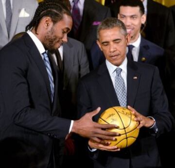 El presidente estadounidense, Barack Obama recibe un balón autografiado de manos del jugador Kawhi Leonard.